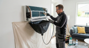 Nettoyage thermopompe saint-jean Technicien de Lavage MD nettoyant les serpentins d'une thermopompe murale avec un sac de r&eacute;cup&eacute;ration d'eau et un jet haute pression &agrave; Saint-Jean-sur-Richelieu.