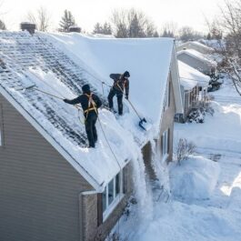 Déneigement Toiture Saint-Jean Technicien de Lavage MD effectuant le déneigement manuel d'une toiture en pente avec une pelle appropriée à Saint-Jean-sur-Richelieu.